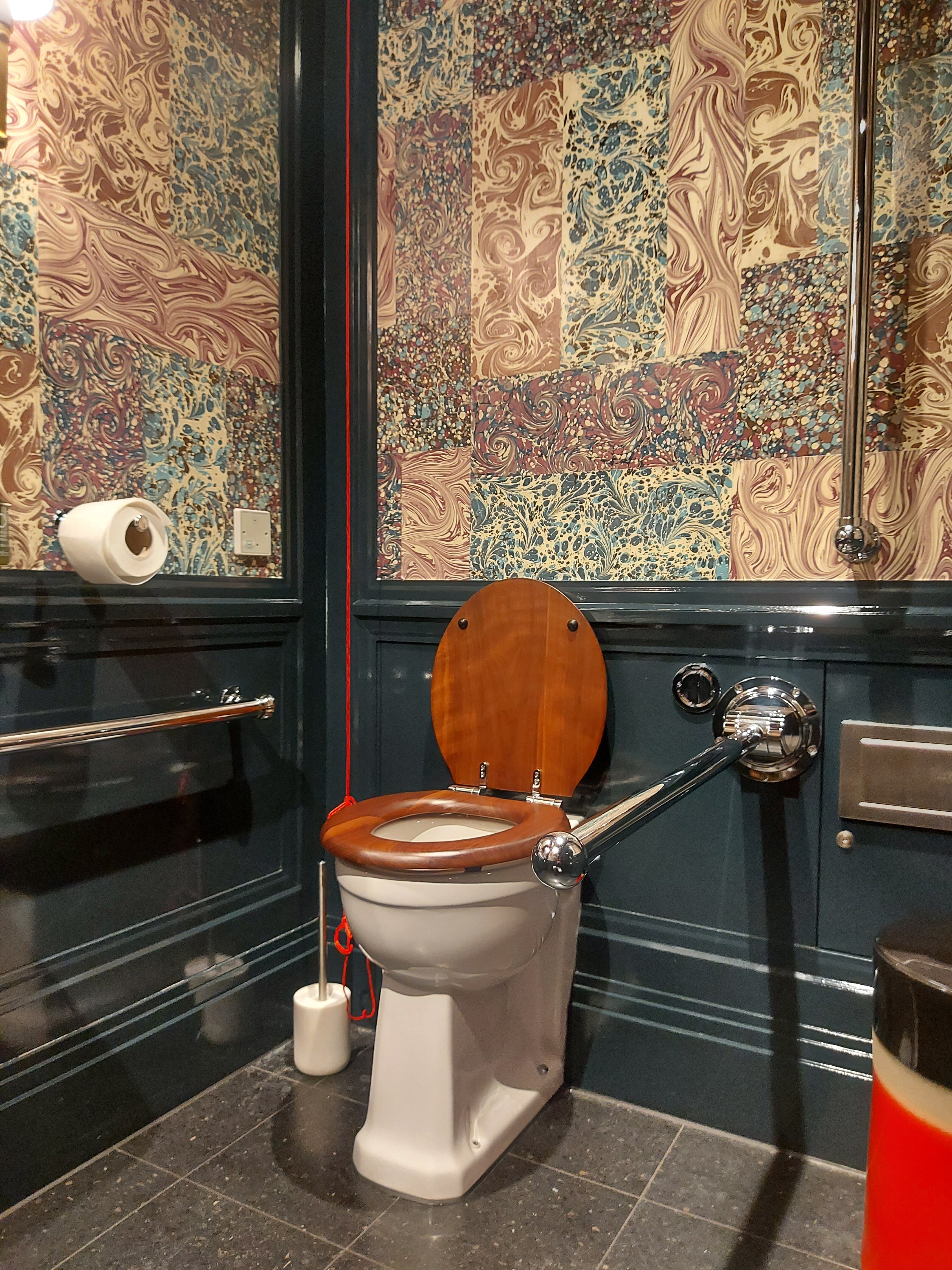 Classic guest bathroom with stainless steel accessory bathroom equipment, blue wooden wall cladding and colourful wallpaper