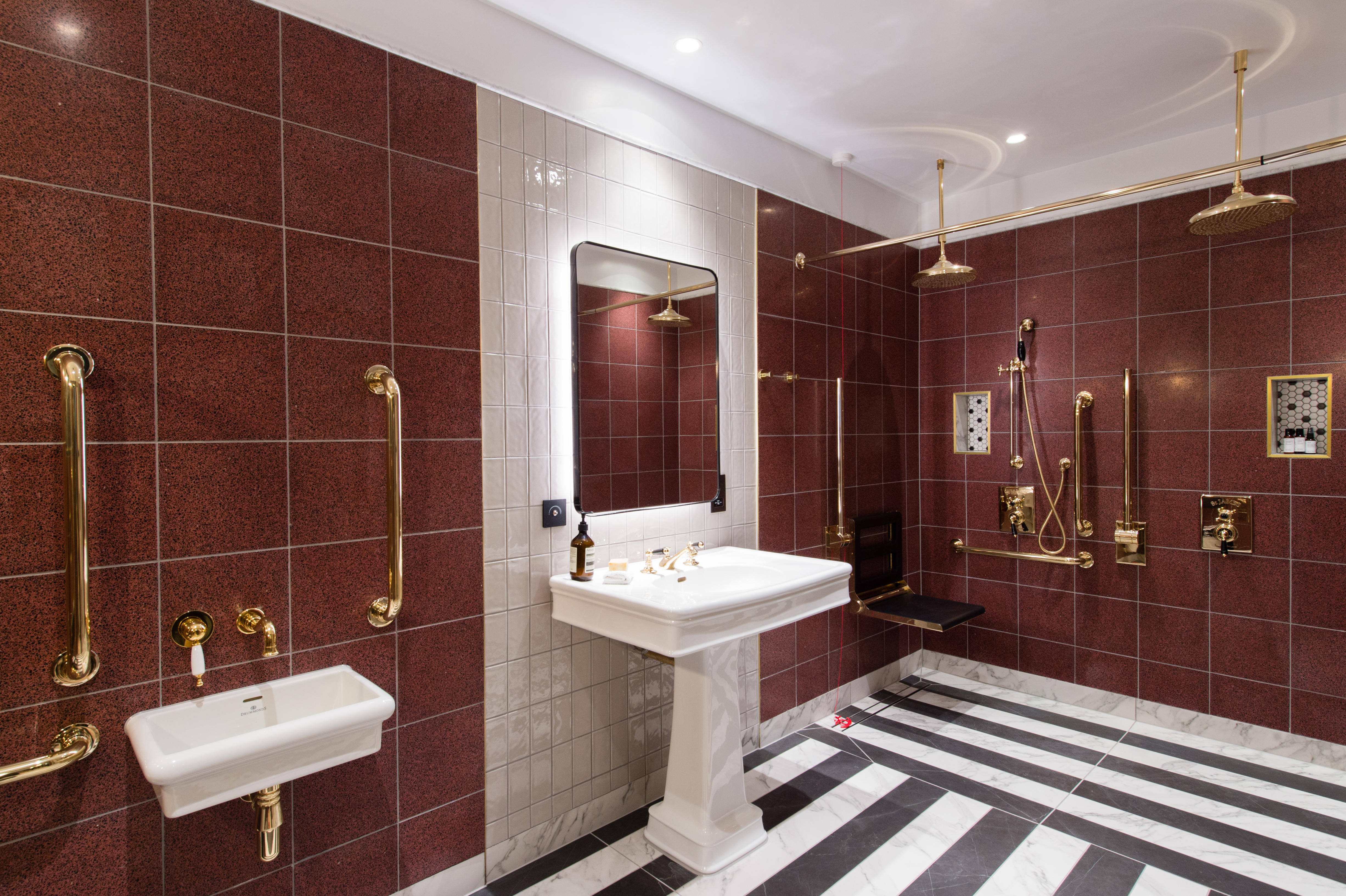 Modern, high-end shower and basin.  Accessible bathroom grab rail next to fold back showering seat and solid brass taps. 