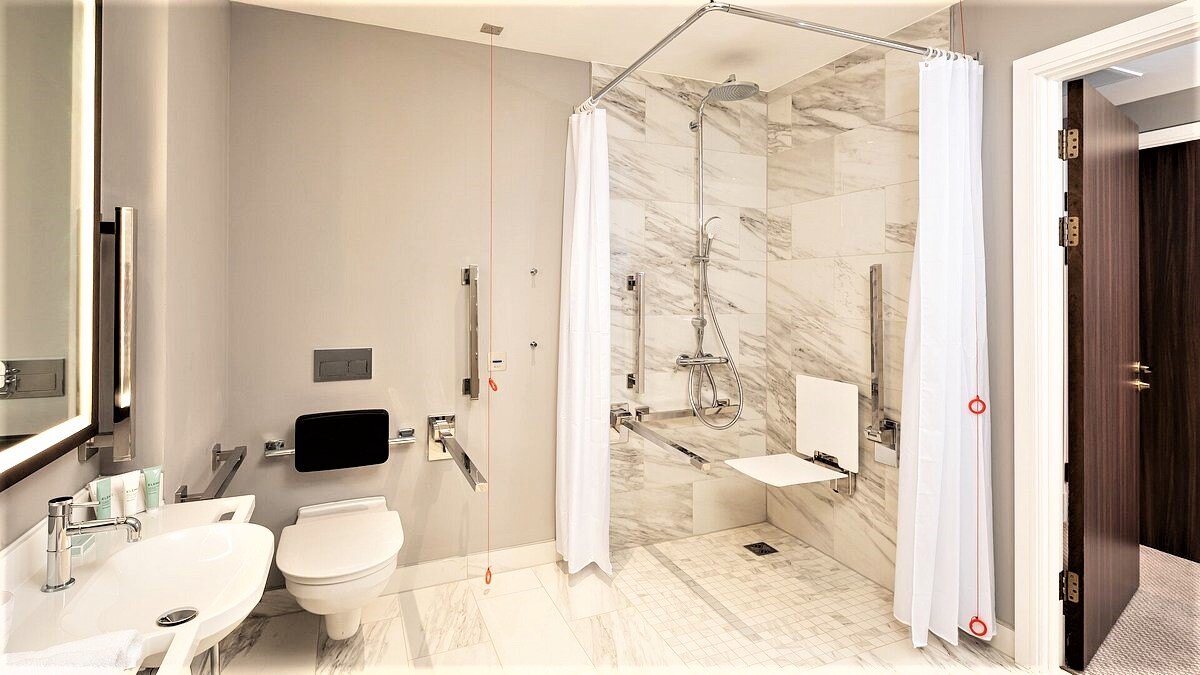 A sophisticate accessible bathroom and shower with wall mounted shower seat in white and stainless steel accessibles for accessible bathroom equipment 