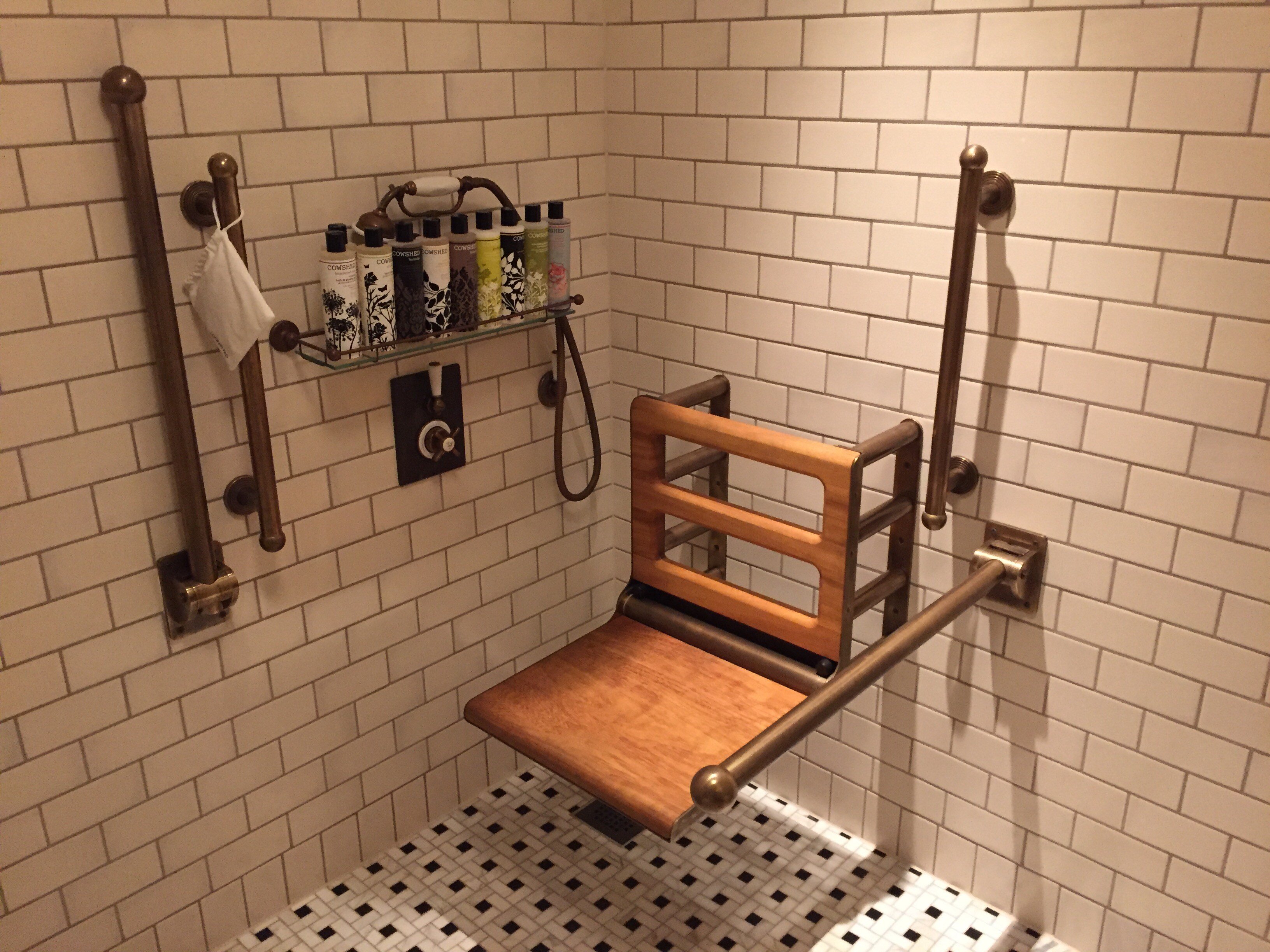 Frame Wall Mounted Fold Down Shower Seat in Wood surrounded by solid brass accessible bathroom accessories